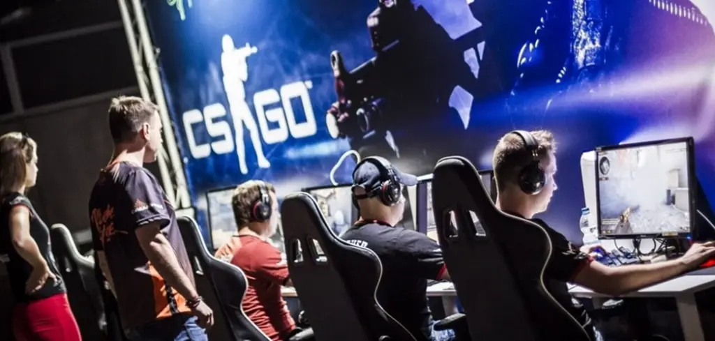 E-sportspelers die Counter-Strike: Global Offensive spelen op een professioneel podium met grote schermen op de achtergrond.